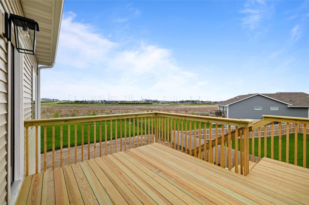 Elevated wood deck with natural wood railings and open green field views in Waukee Iowa new construction home