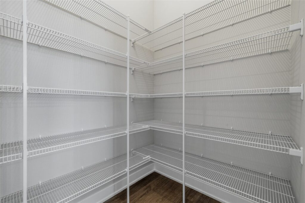 Spacious walk-in pantry with floor to ceiling wire shelving on three walls and dark wood floor in Waukee Iowa new build