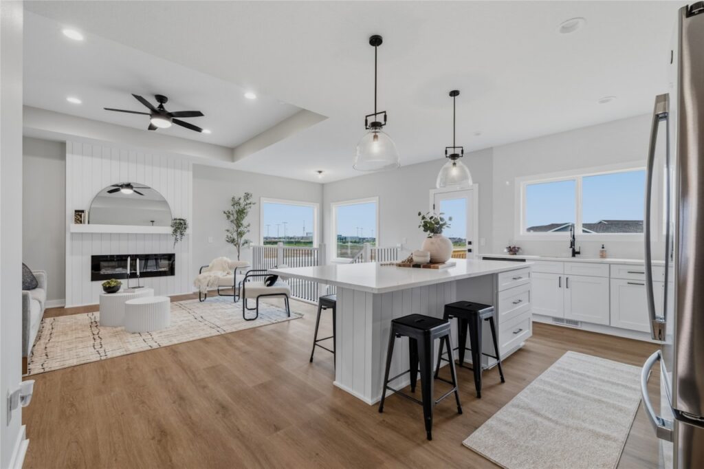 Open concept kitchen and living room with shiplap fireplace, large windows, and quartz island in Waukee Iowa new construction home