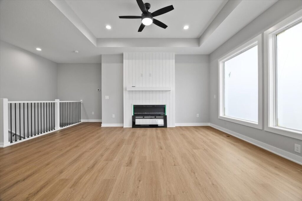 Bright white room with hardwood floors and a ceiling fan, featured in homes for sale at 321 11th St NW, Bondurant, IA.