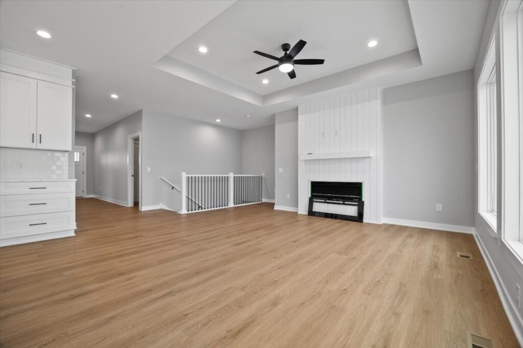 Bright white room with hardwood floors and a ceiling fan, featured in homes for sale at 321 11th St NW, Bondurant, IA.