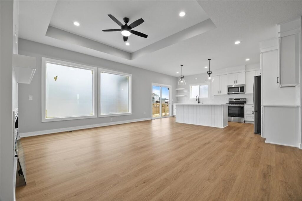 Bright white room with hardwood floors and a ceiling fan, featured in homes for sale at 321 11th St NW, Bondurant, IA.