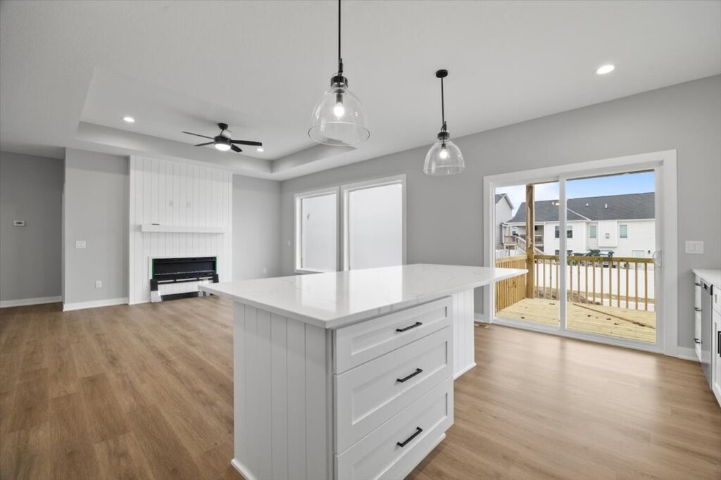 A kitchen featuring white cabinets and hardwood floors, part of the available homes for sale at 321 11th St NW, Bondurant, IA.