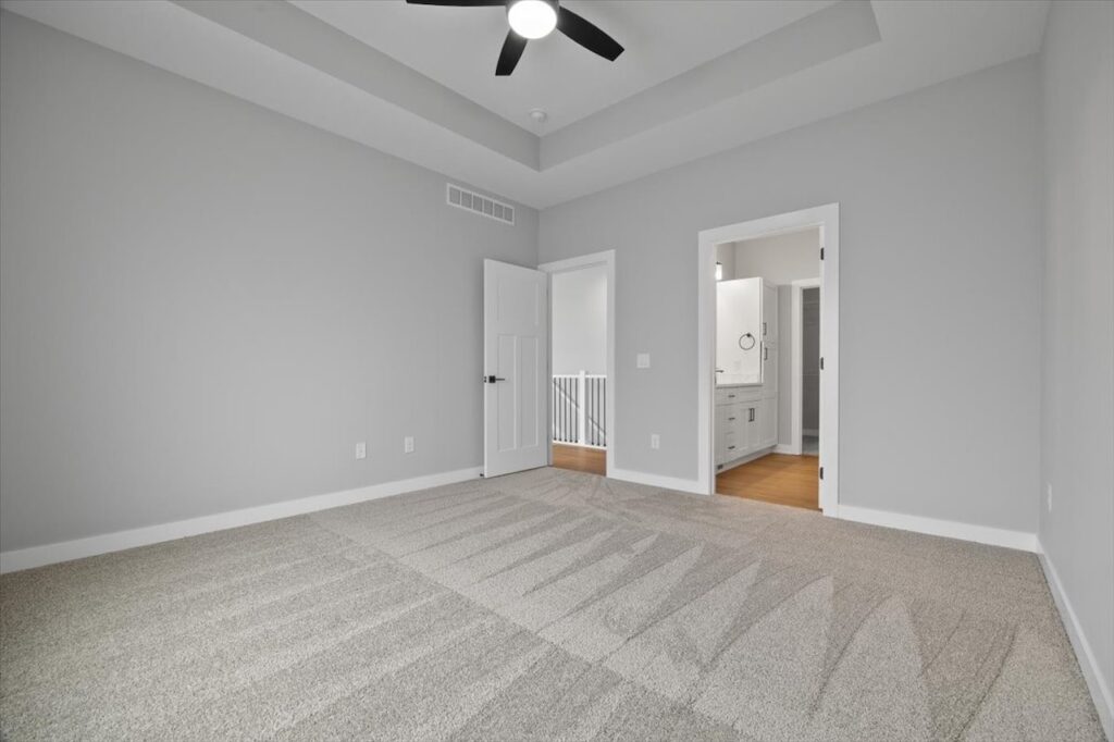 Empty room featuring carpet and a ceiling fan, part of available homes for sale at 321 11th St NW, Bondurant, IA.