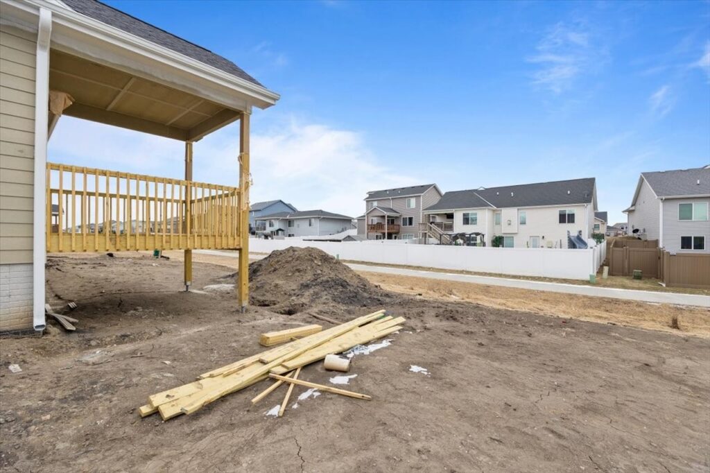 A wooden deck in a backyard with a house, showcasing available homes for sale at 321 11th St NW, Bondurant, IA.