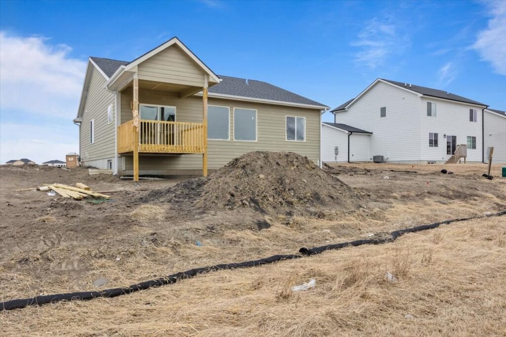 A backyard featuring a wooden deck and a house, highlighting available homes for sale at 321 11th St NW, Bondurant, IA.