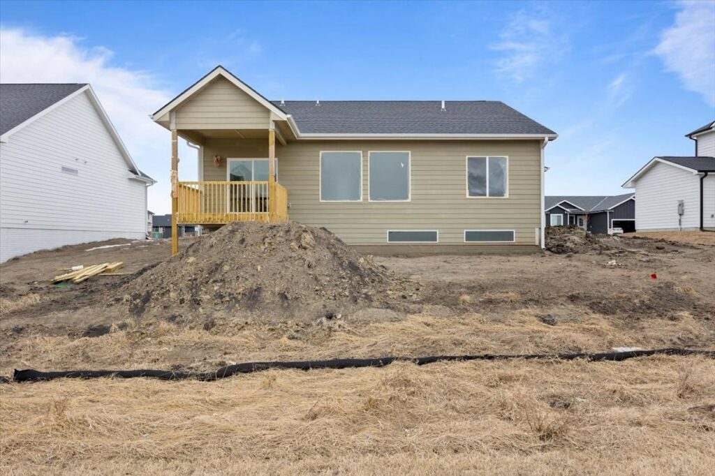A backyard featuring a wooden deck and a house, highlighting available homes for sale at 321 11th St NW, Bondurant, IA.