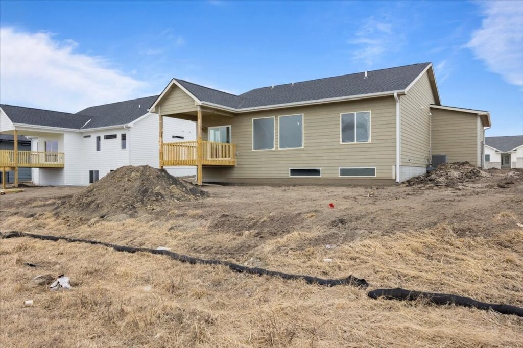 A backyard featuring a wooden deck and a house, highlighting available homes for sale at 321 11th St NW, Bondurant, IA.