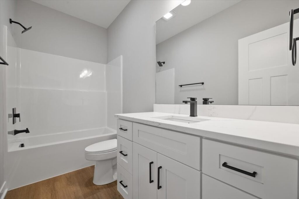 A bathroom featuring white cabinets and a toilet, part of the available homes for sale at 321 11th St NW, Bondurant, IA.