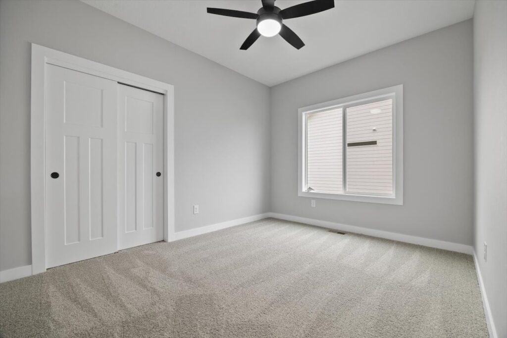 A bathroom featuring white cabinets and a toilet, part of the available homes for sale at 321 11th St NW, Bondurant, IA.