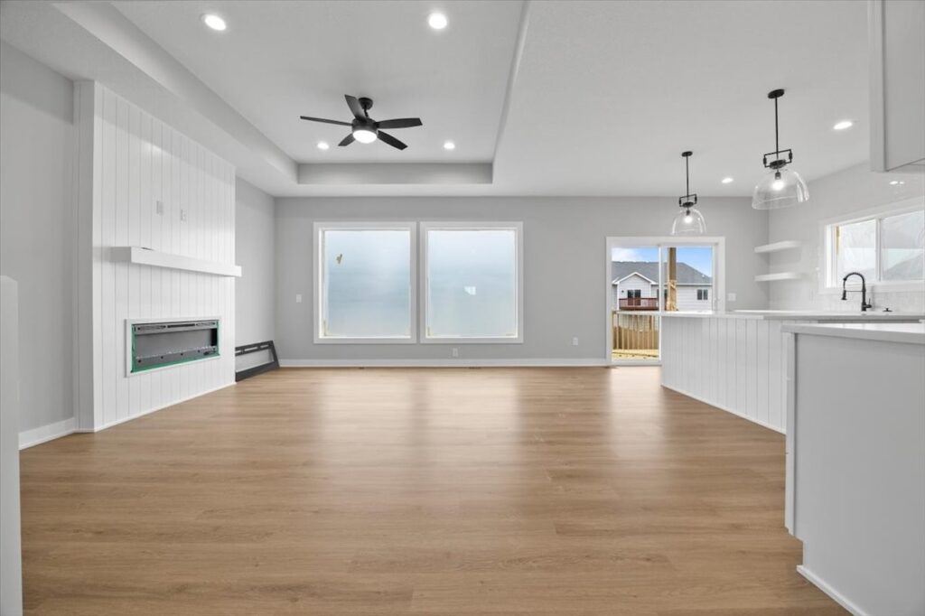 Bright white room with hardwood floors and a ceiling fan, featured in homes for sale at 321 11th St NW, Bondurant, IA.