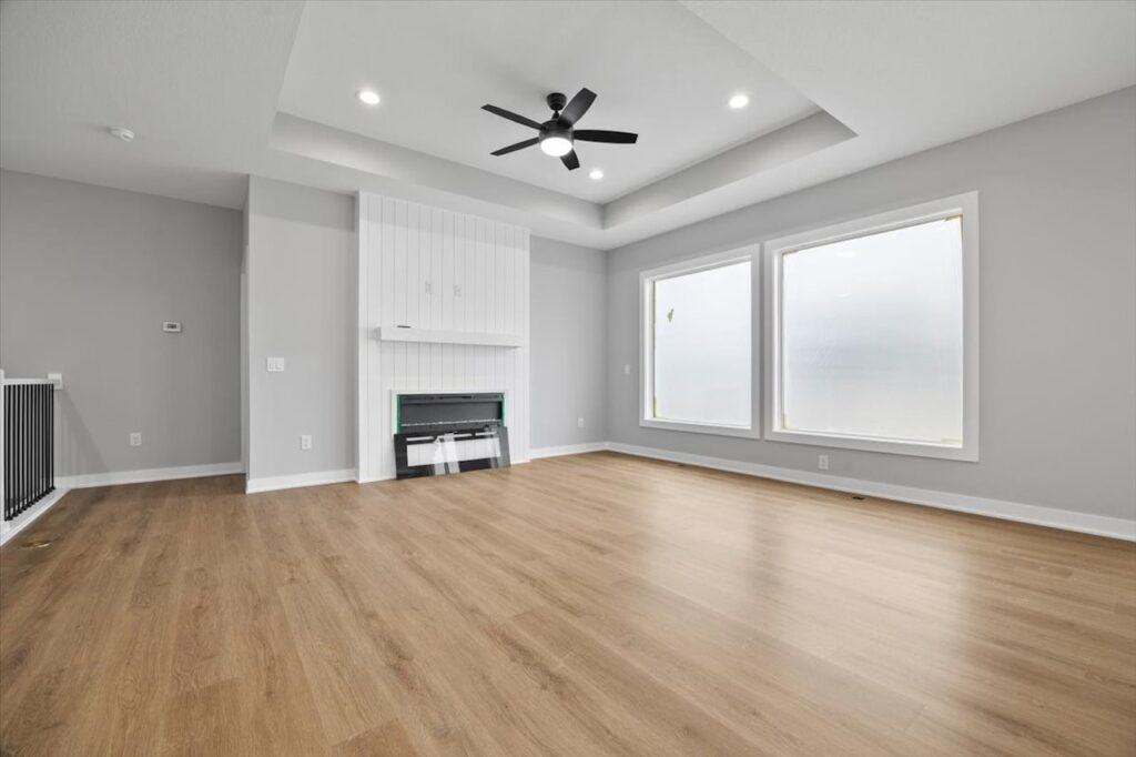 Bright white room with hardwood floors and a ceiling fan, featured in homes for sale at 321 11th St NW, Bondurant, IA.