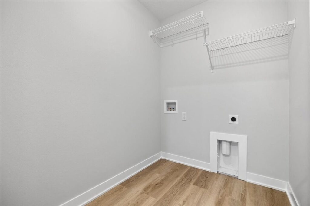 Interior of an empty room with a white wall and wooden floor, listed for sale at 675 NW Rosemont Dr, Waukee, IA by Gladiator Homes.