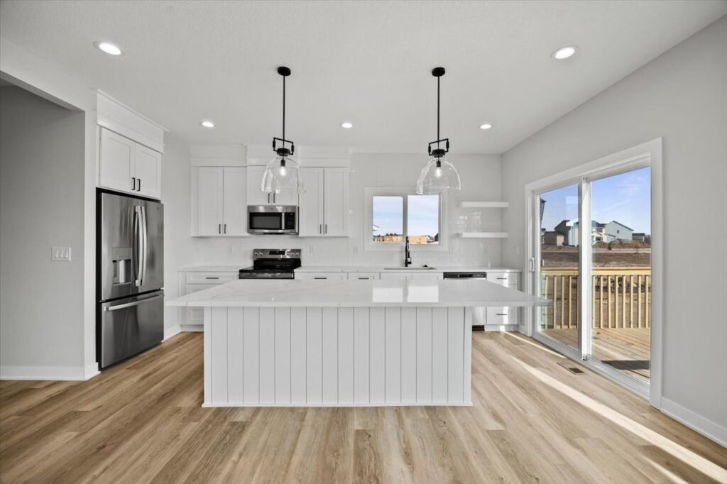 Kitchen featuring white cabinets and hardwood floors, part of the home for sale at 675 NW Rosemont Dr, Waukee, IA.