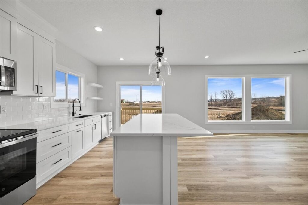 Modern kitchen showcasing white cabinets and hardwood floors, located in the home for sale at 675 NW Rosemont Dr, Waukee, IA.