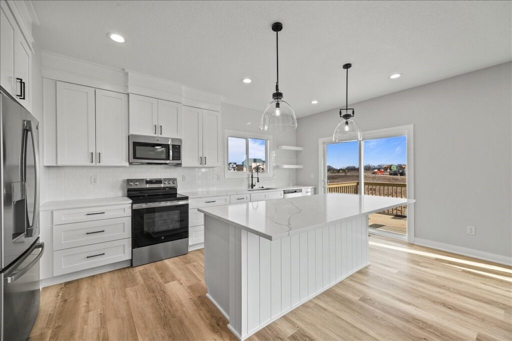 Modern kitchen showcasing white cabinets and hardwood floors, located in the home for sale at 675 NW Rosemont Dr, Waukee, IA.