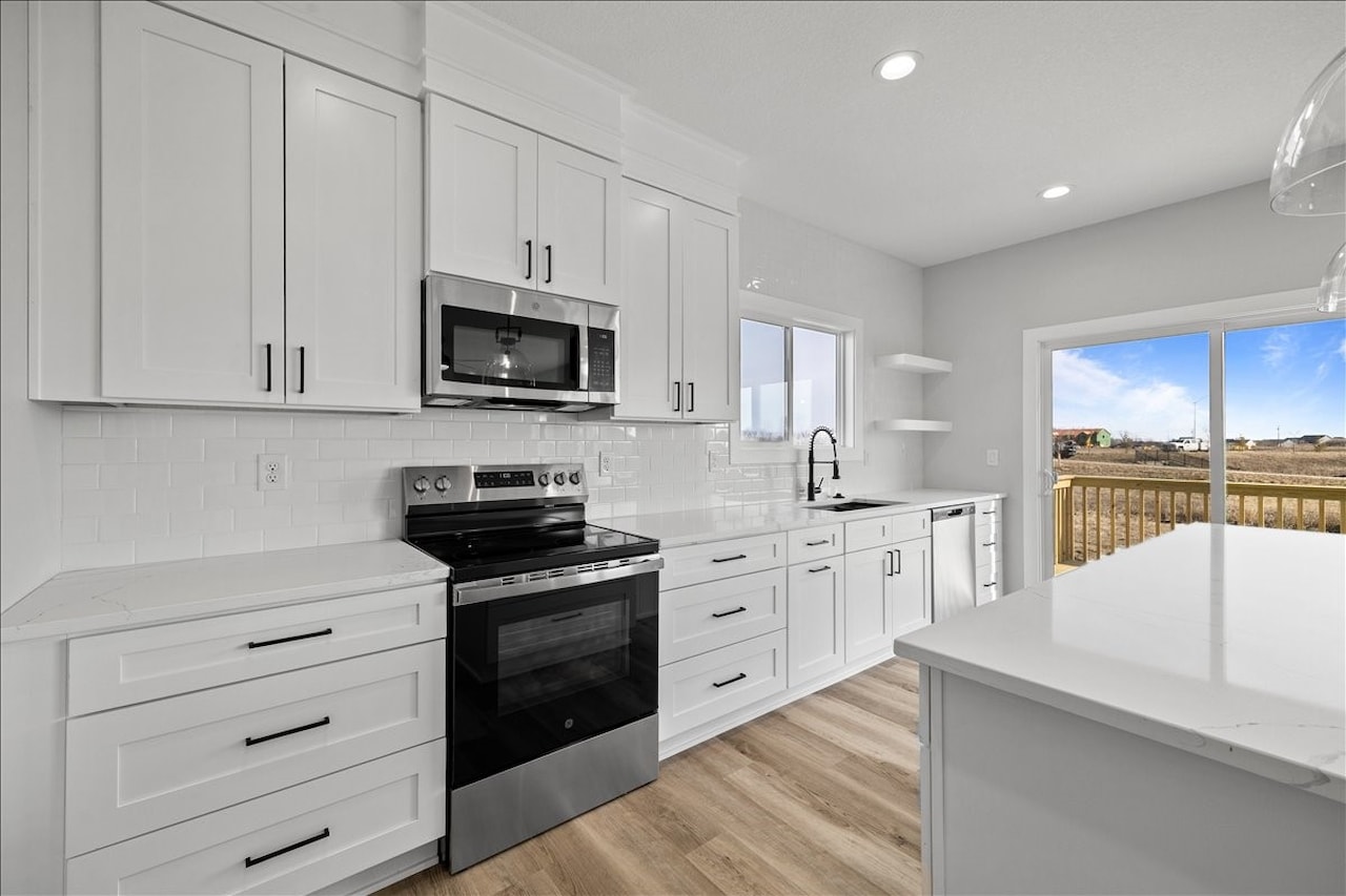 Sleek white kitchen equipped with stainless steel appliances, for sale at 675 NW Rosemont Dr, Waukee, IA by Gladiator Homes