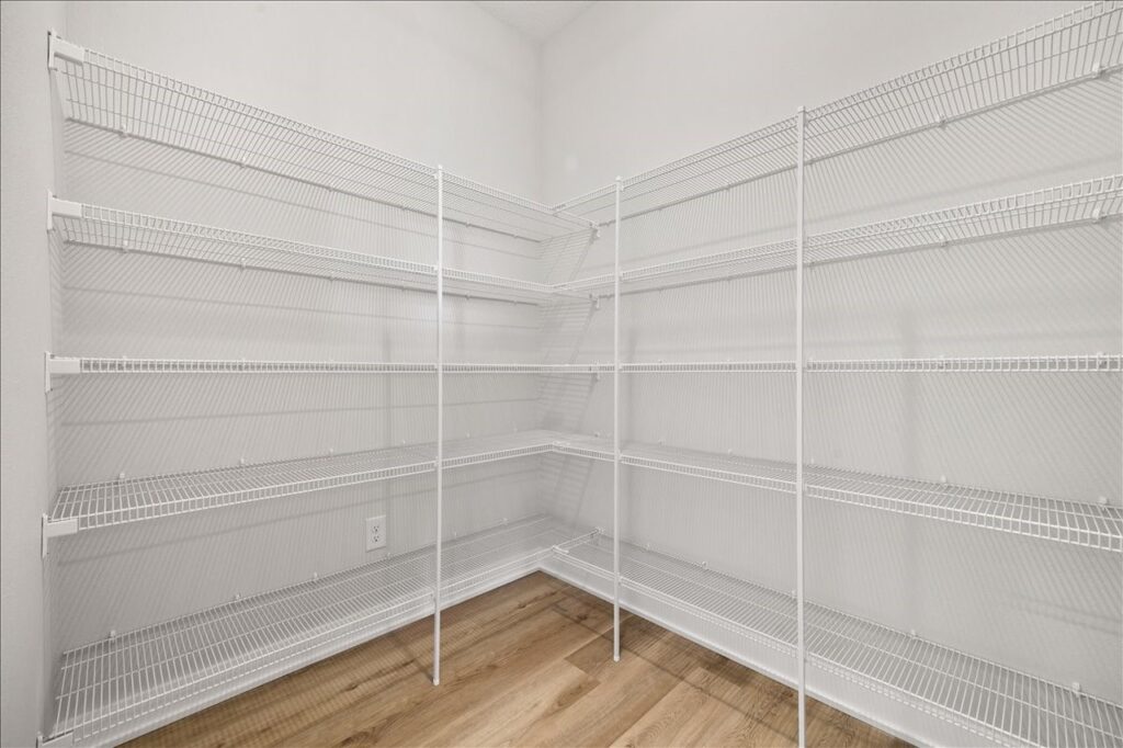 Interior of a white pantry showcasing shelves and a wooden floor, part of the property at 675 NW Rosemont Dr, Waukee, IA.