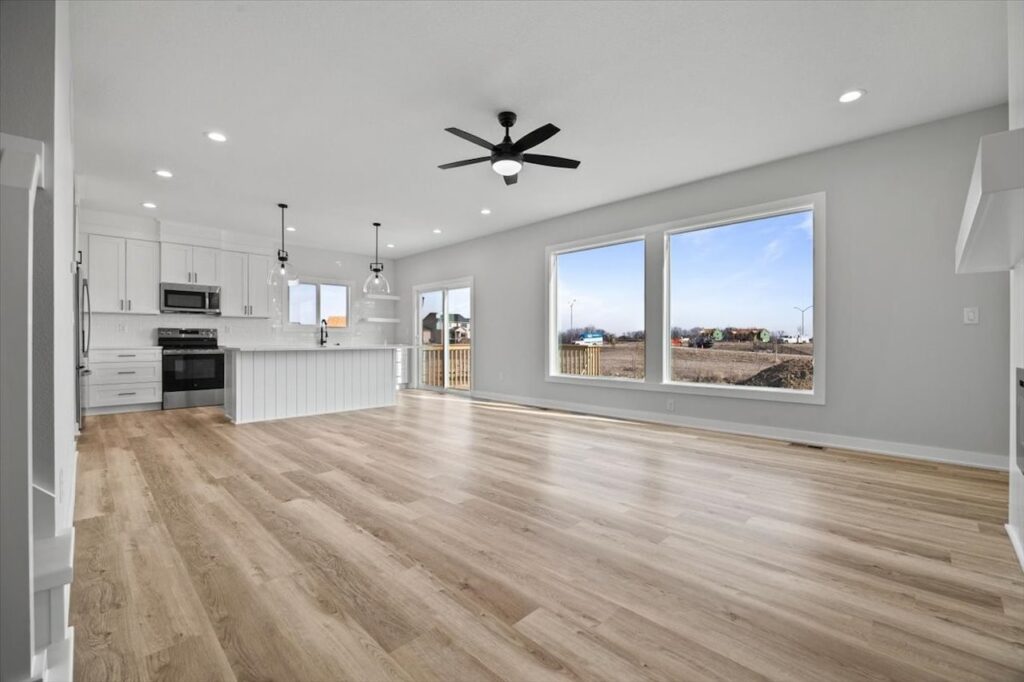 Large open kitchen with hardwood floors and a ceiling fan, featured in the home for sale at 675 NW Rosemont Dr, Waukee, IA.