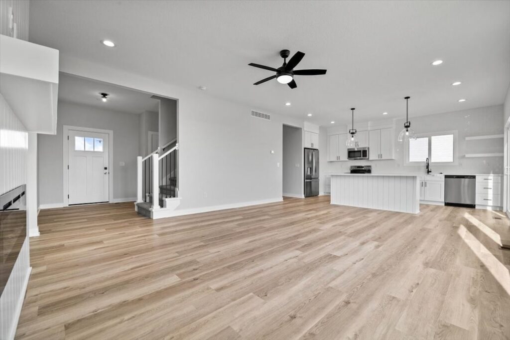 Spacious kitchen showcasing hardwood floors and a ceiling fan, part of the home for sale at 675 NW Rosemont Dr, Waukee, IA.