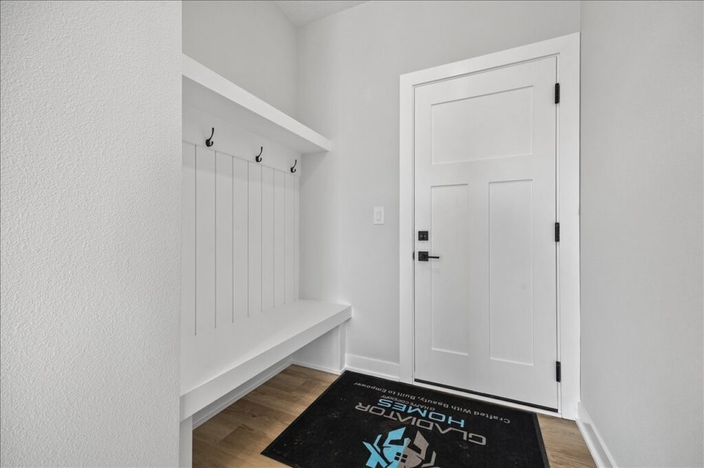 Entrance view showing a white door, black mat, and bench, part of the property for sale at 675 NW Rosemont Dr, Waukee, IA.