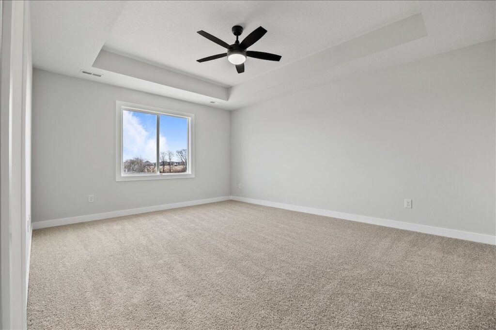 Spacious empty living room with hardwood floors and a ceiling fan, listed for sale at 675 NW Rosemont Dr, Waukee, IA.