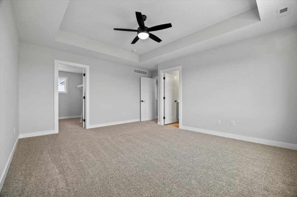 Spacious empty living room with hardwood floors and a ceiling fan, listed for sale at 675 NW Rosemont Dr, Waukee, IA.