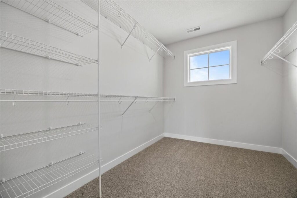 Bright white pantry with organized shelves and wooden flooring, available in the home for sale at 675 NW Rosemont Dr, Waukee, IA.