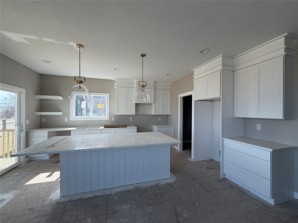 Luxury modern kitchen with white shaker cabinets, quartz island, pendant lighting, and open-concept layout in Gladiator Homes property for sale at 665 Rosemont Dr, Waukee, Iowa.