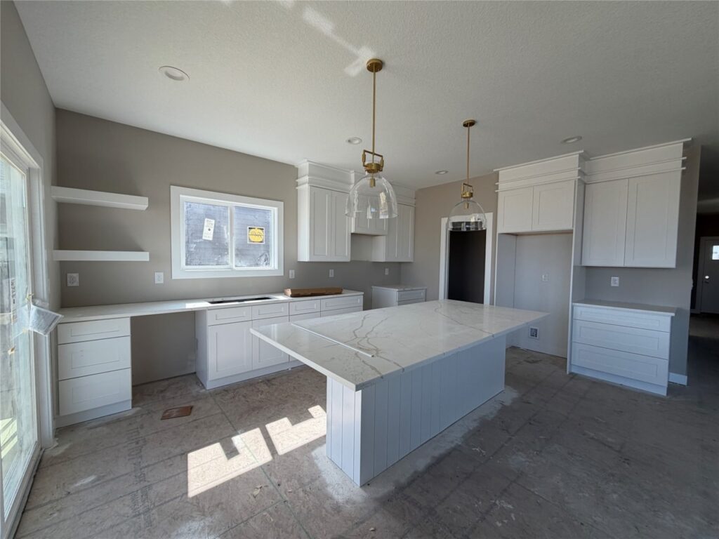 Luxury modern kitchen with white shaker cabinets, quartz island, pendant lighting, and open-concept layout in Gladiator Homes property for sale at 665 Rosemont Dr, Waukee, Iowa.