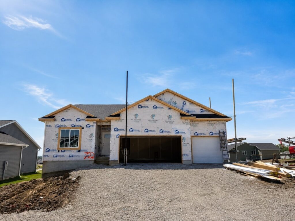 Construction site of a home with a garage, under a sunny blue sky, situated at 722 W Wright Rd, Norwalk, IA.