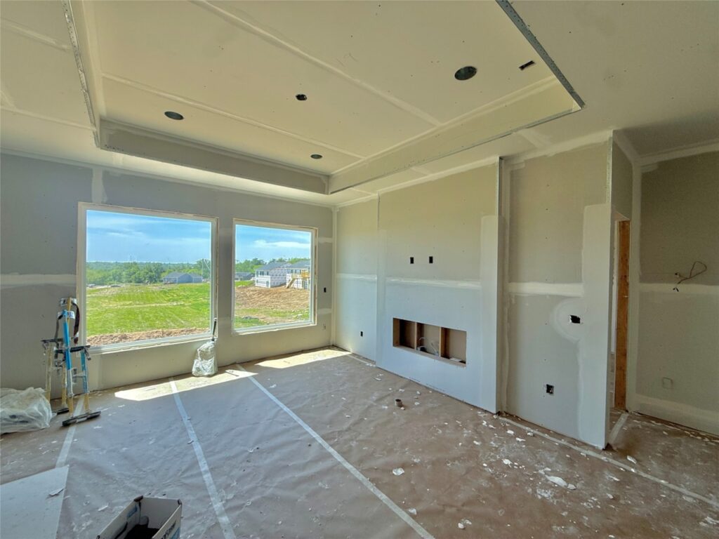 Interior view of a room featuring a fireplace and unfinished drywall, showcasing a new construction home in Norwalk, IA.