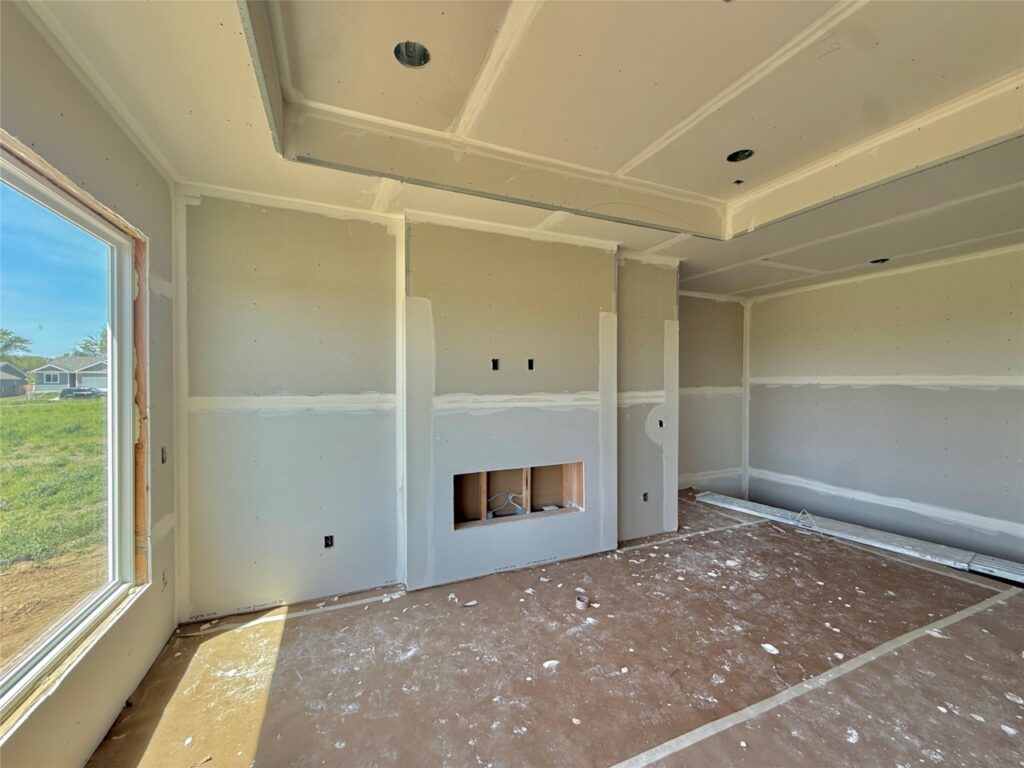 A cozy room displaying a fireplace and drywall, part of new construction homes for sale at 722 W Wright Rd, Norwalk, IA.