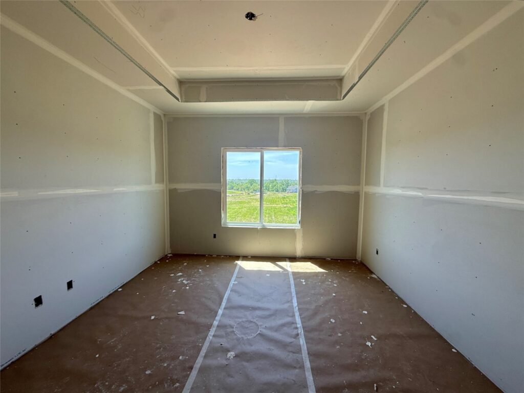 Interior view of a room featuring a window and unfinished drywall walls in a new construction home in Norwalk, IA.