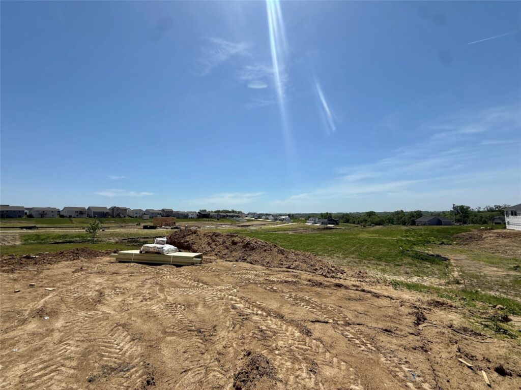 A construction site with a house and a truck on a dirt field, showcasing available homes for sale at 722 W Wright Rd, Norwalk, IA.